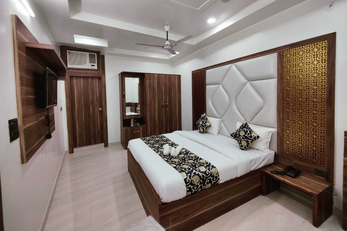 A modern bedroom with a large bed, a wardrobe, a vanity with a mirror, and a ceiling fan.