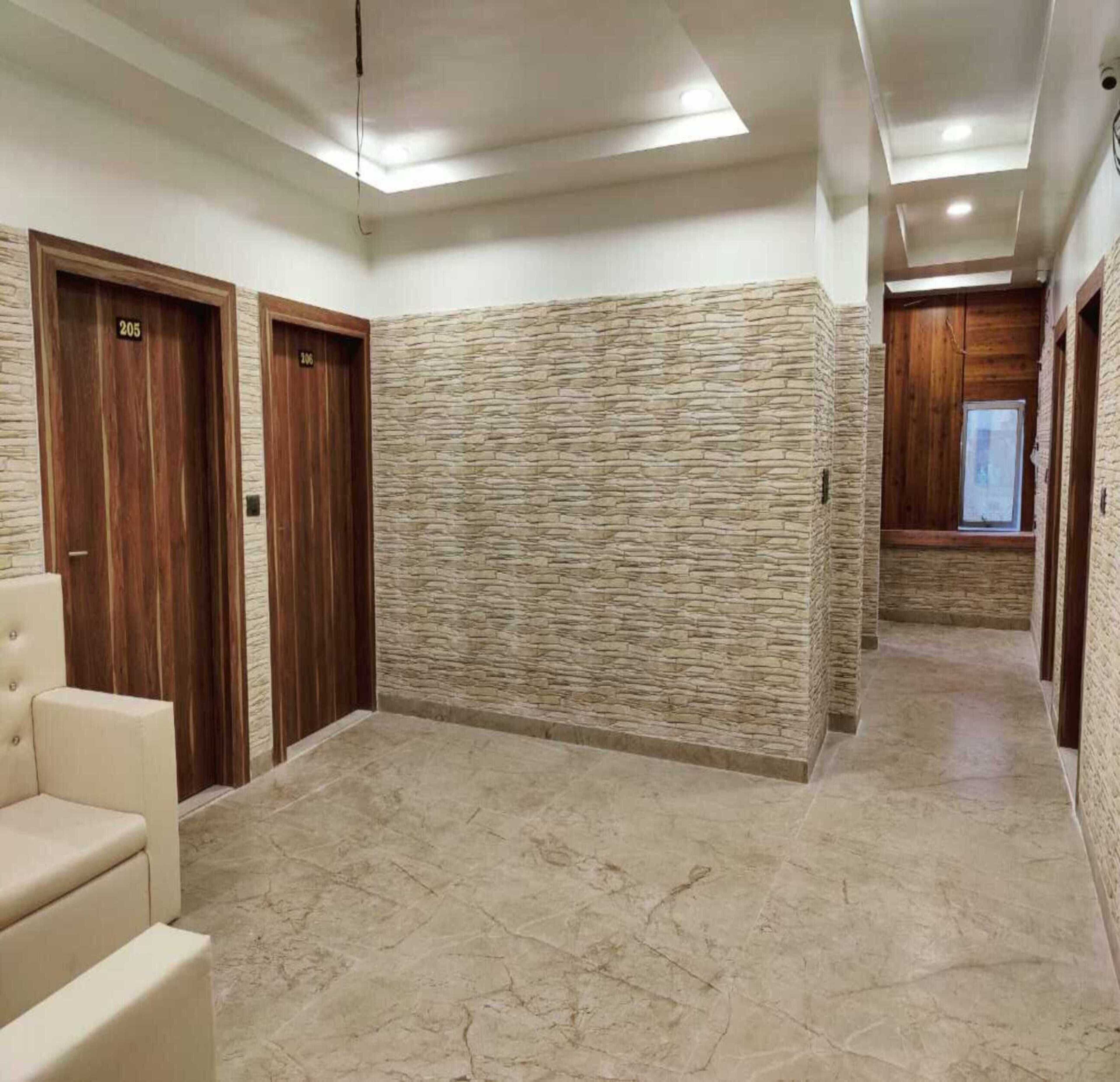 A hallway with stone walls, wooden doors, and a marble floor.