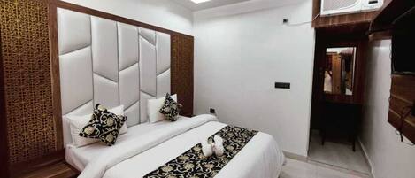 Un dormitorio con una cama grande, ventilador de techo, unidad de aire acondicionado y un panel de madera en la pared.