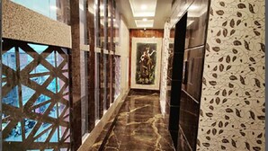 A marble-floored corridor with patterned walls, a framed artwork, and a view through a geometric window. - Hotel Royal Vrindavan (Aligarh)