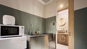 A compact kitchenette with a microwave, sink, and stainless steel cabinets. - Hotel Kanma Ueno (Tokyo)