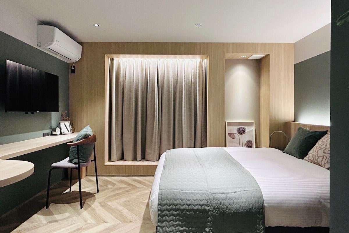 Una habitación de hotel moderna con una cama, un escritorio, una silla, un televisor y una ventana con cortinas.
