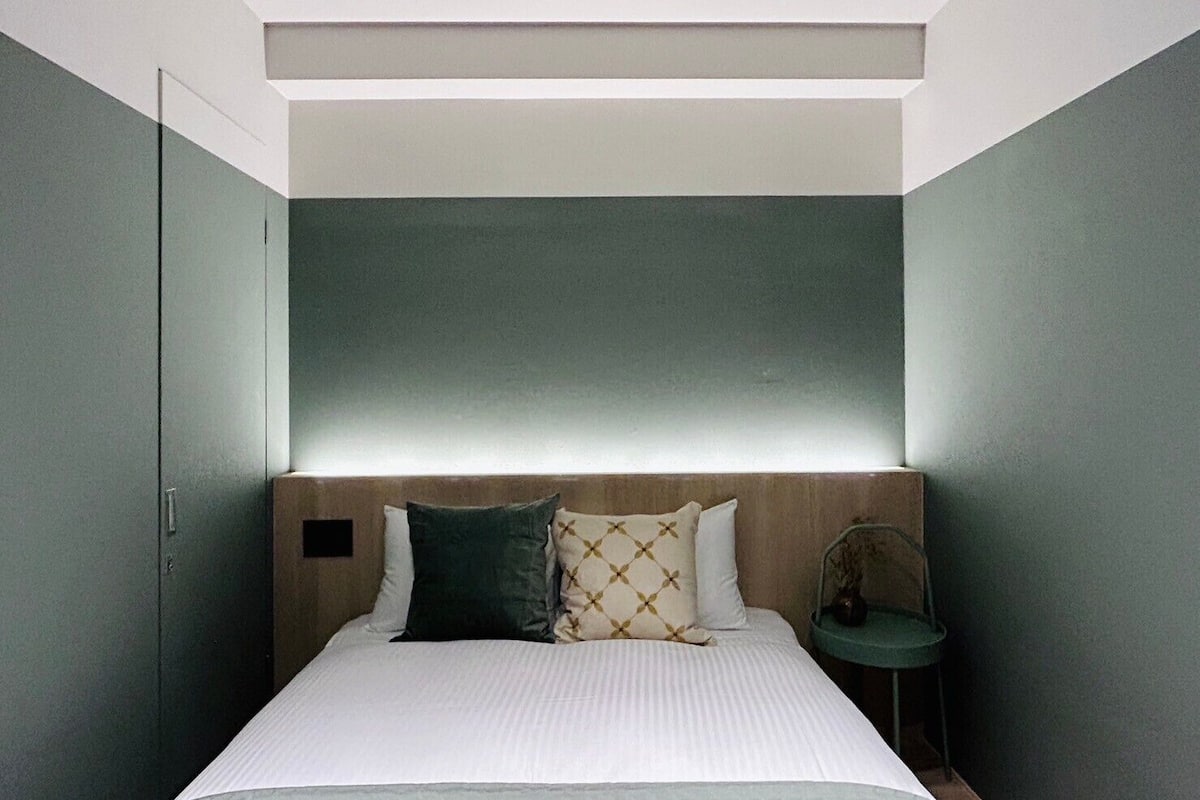 Un dormitorio con cama, mesita de noche y cabecero.