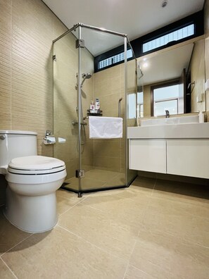 A modern bathroom with a glass-enclosed shower, a toilet, and a vanity with a mirror. - Vinhomes Skylake - SunhouseLand (Hanoi)