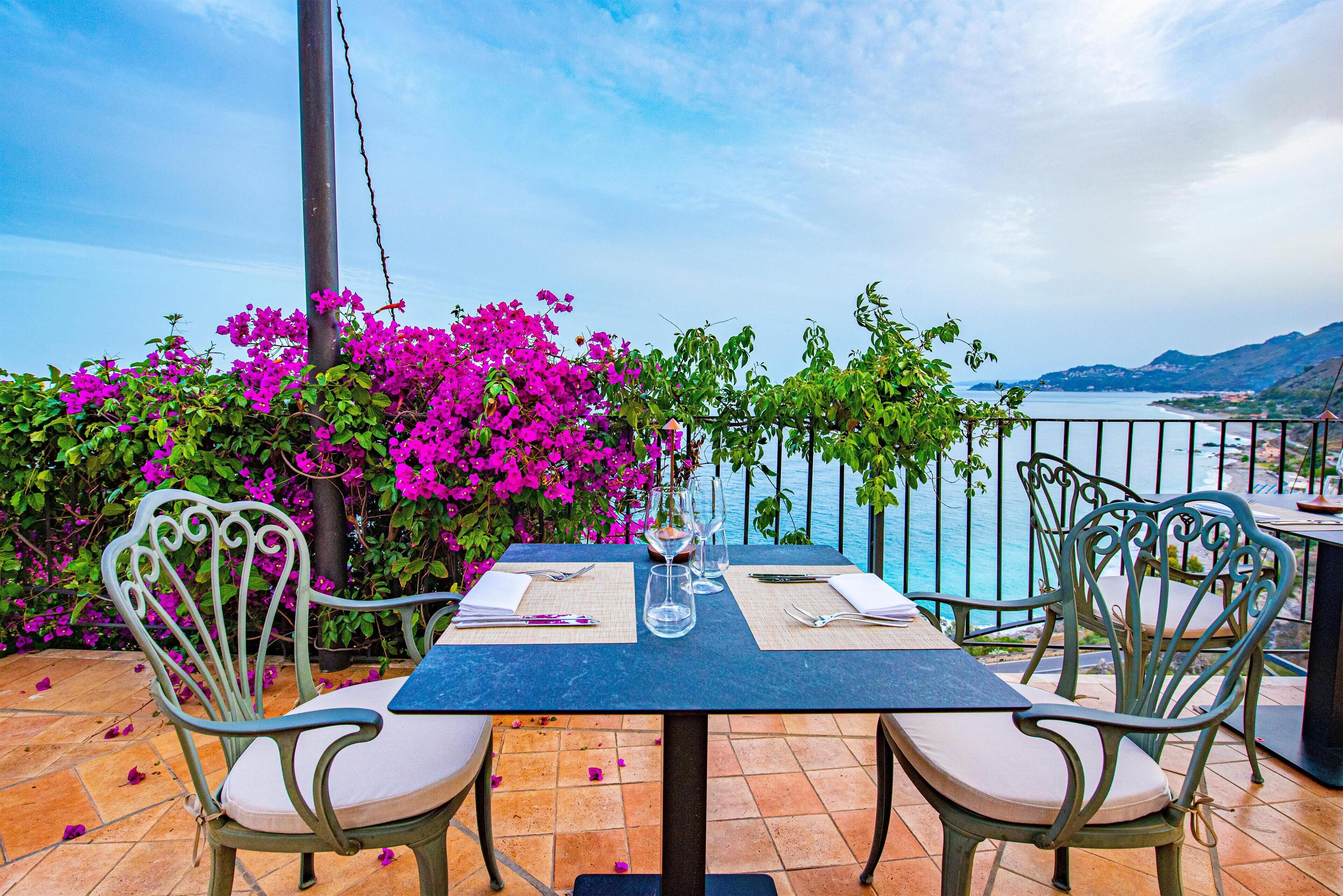 A table set for two with a view of the sea and mountains.