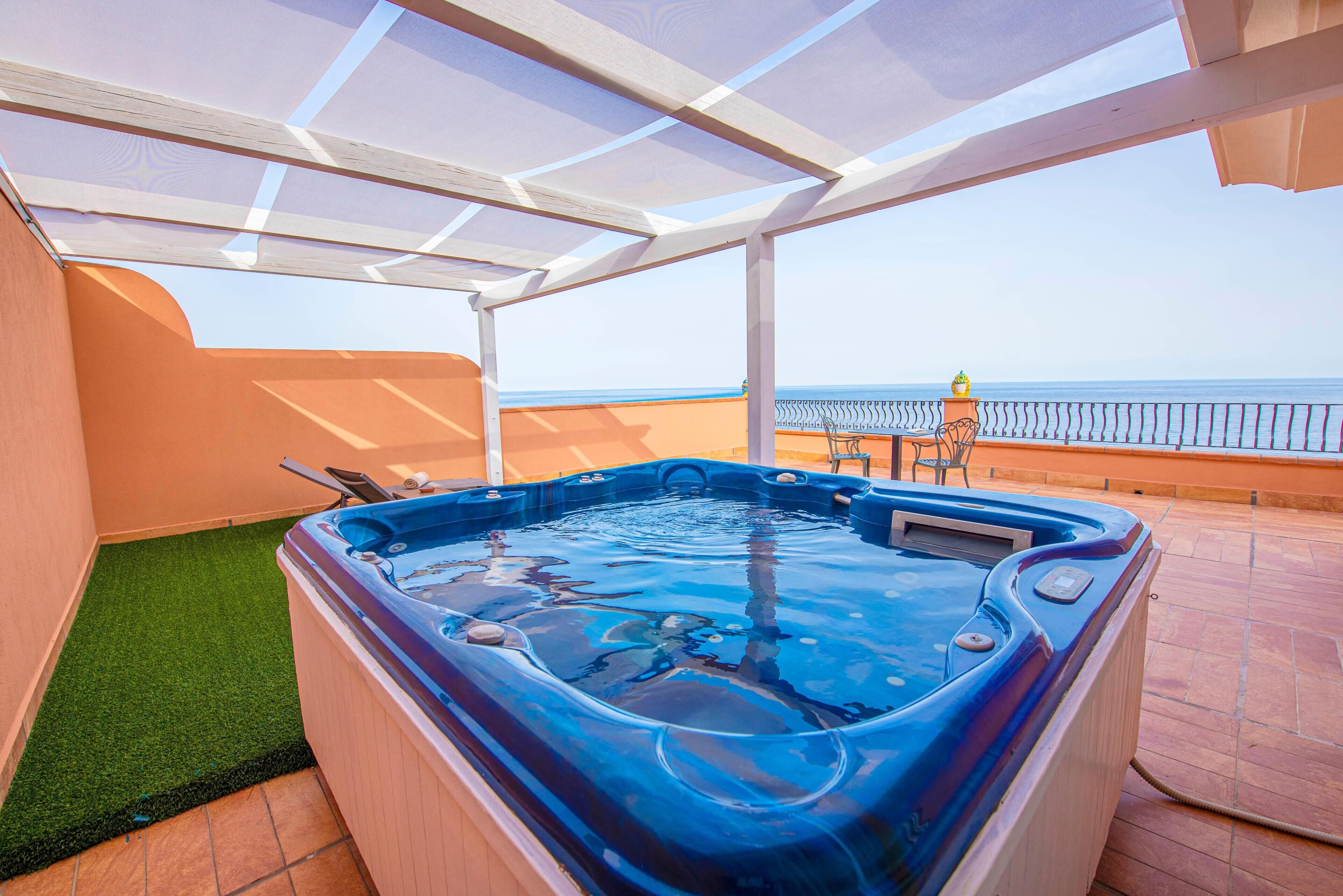 Un jacuzzi en un patio cubierto con vista al mar.