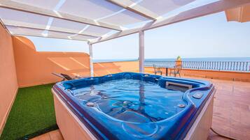 Un jacuzzi en un patio cubierto con vista al mar.