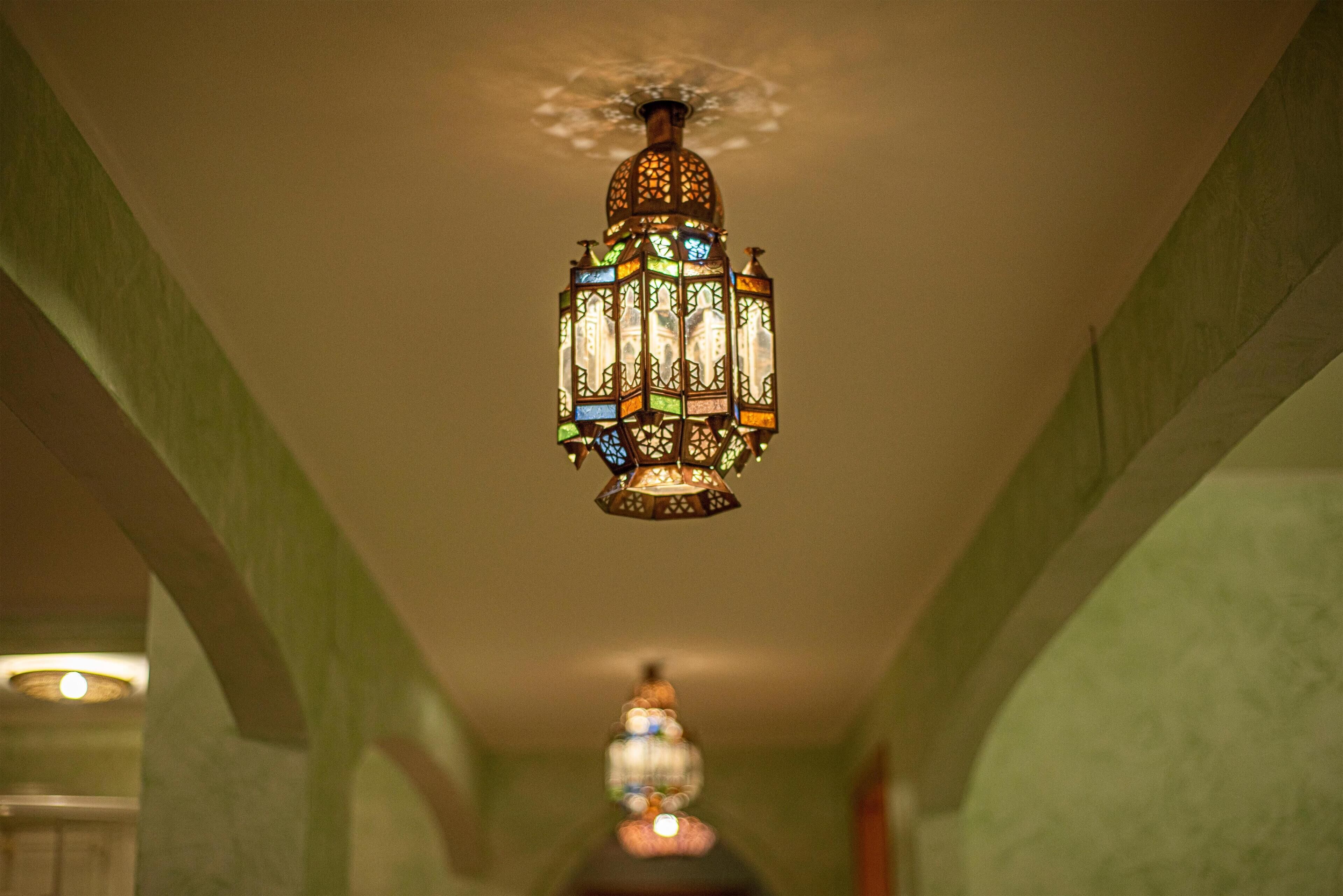 Une lanterne suspendue, ornée de motifs complexes et composée de plusieurs panneaux de verre coloré.