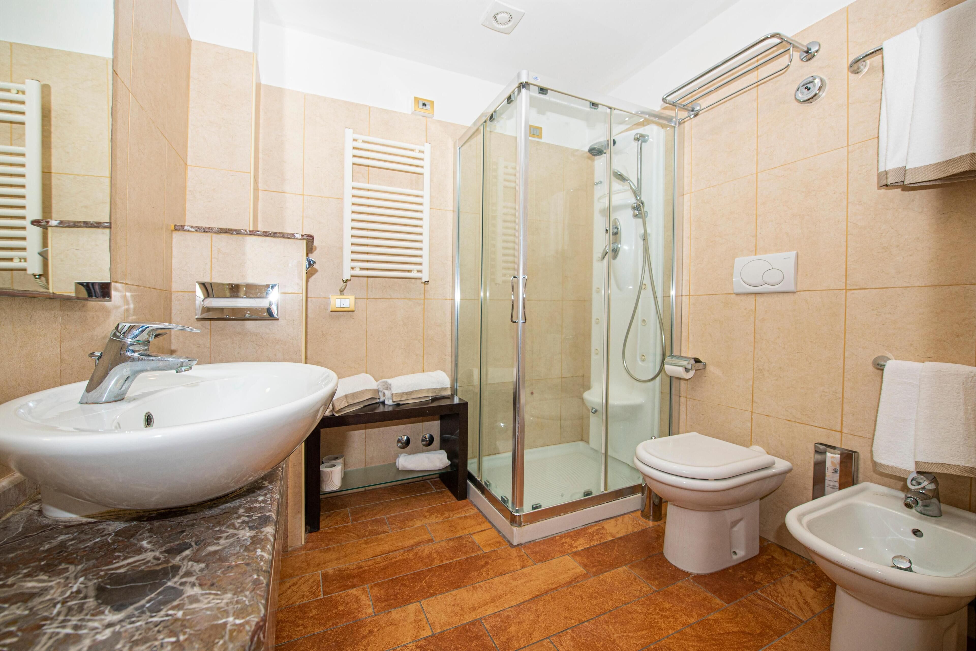 Un baño con ducha de mampara, lavamanos, inodoro y bidé.