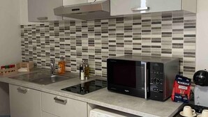 Une cuisine moderne équipée d’un four à micro-ondes, d’un évier et d’un pare-feu en carreaux.