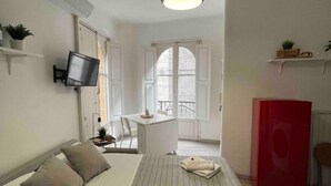 Une chambre  à coucher avec un lit, un téléviseur fixé au mur, une armoire rouge et une fenêtre donnant sur un beau paysage.