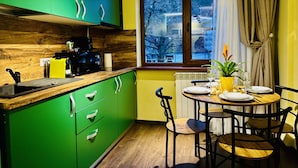 A modern kitchen with green cabinets, a wooden countertop, and a dining area with a round table and chairs.