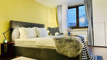 A bedroom with a bed, bedside lamp, and a window with curtains.