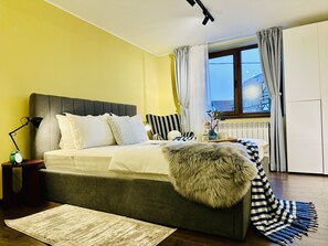 A bedroom with a bed, bedside lamp, and a window with curtains. - 5 to stay close to the Castle (Bran)