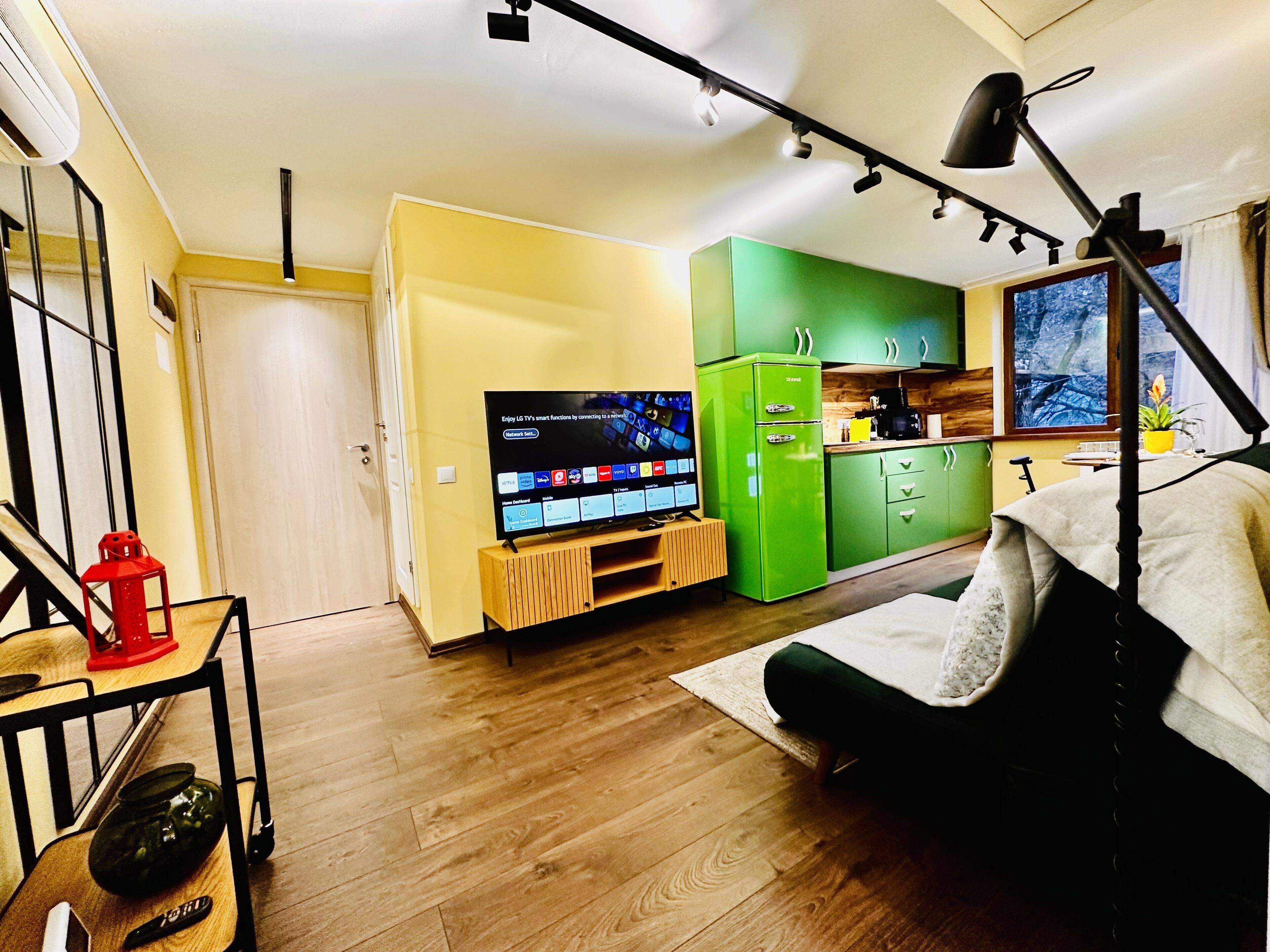 A compact living space with a television, kitchenette, and a dining area.