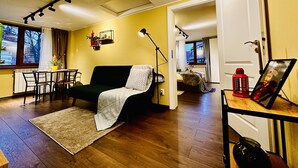 A cozy living room with a sofa, a dining table, and a kitchen area visible through an open door.