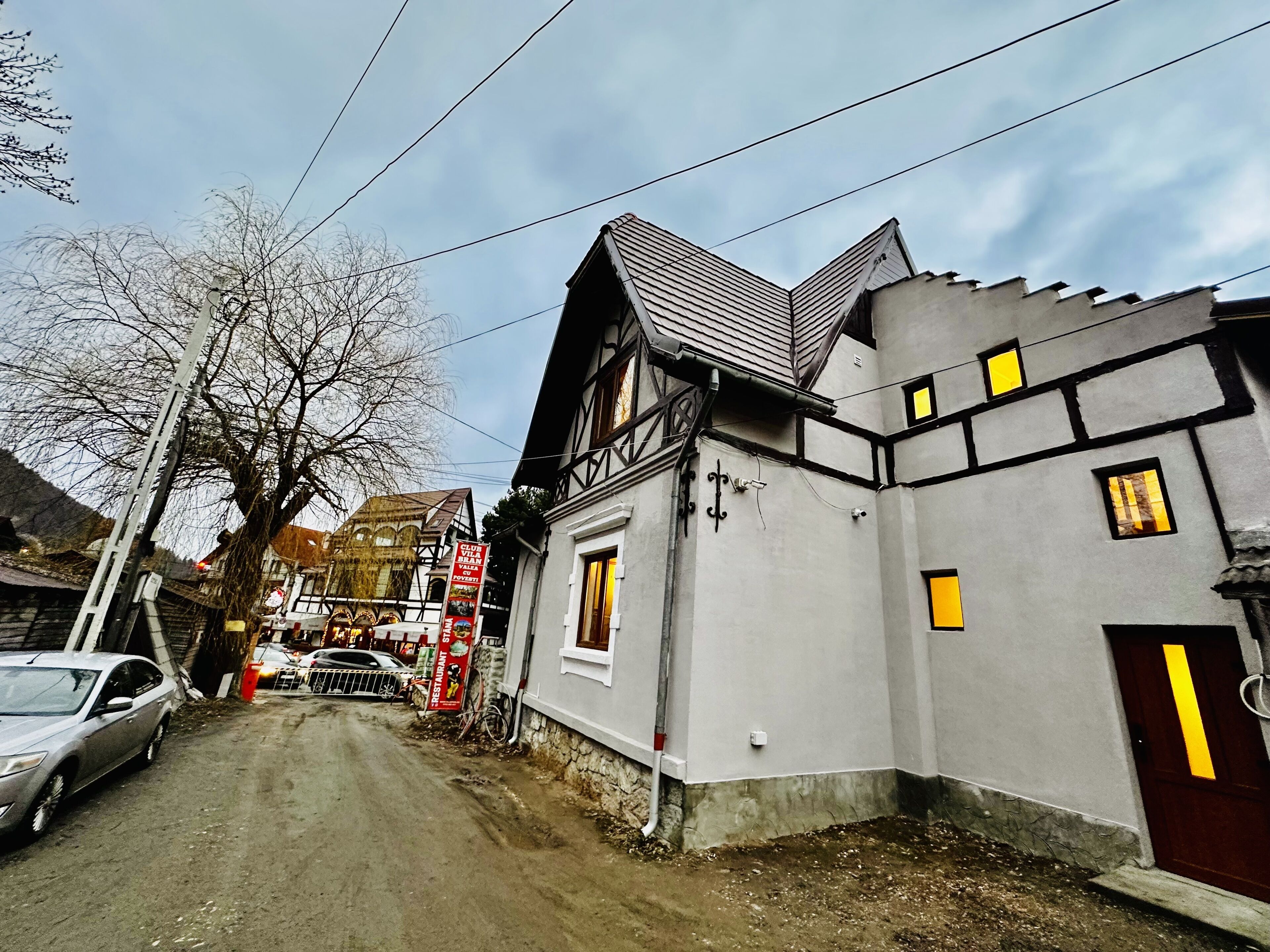 A narrow street with a building featuring a gabled roof and a door with a yellow stripe.