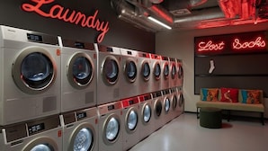 A laundry facility with multiple washing machines and a neon sign reading 'Laundry Lost Socks'. - MILESTONE Krakow Center Student Living by Tribera (Kraków)