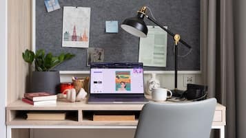 A study area with a desk, laptop, lamp, and a chair.