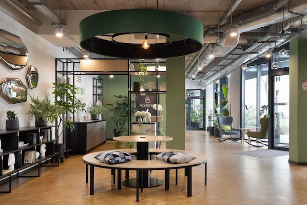 A modern interior with a round table, seating, and potted plants. - MILESTONE Krakow Center Student Living by Tribera (Kraków)