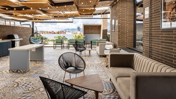 Um bar no terraço com vista para a cidade, apresentando diversas opções de assentos e um espaço de bar.