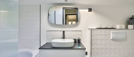 A modern bathroom with a skylight, a round mirror, a white sink, and a bathtub.