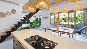 Cozinha moderna com ilha central, fogão preto e escada com degraus de madeira.