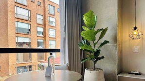 A modern room with a round table, a potted plant, and a view of a brick building. - w * | Cozy Loft in Parque Virrey (Bogotá)