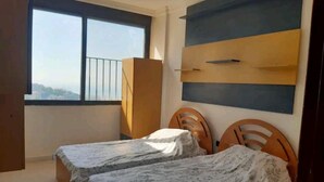 Un dormitorio con dos camas individuales, una ventana con vistas y un armario de madera.