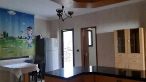 Una cocina con una isla central, un refrigerador, una mesa de comedor y un mural en la pared.