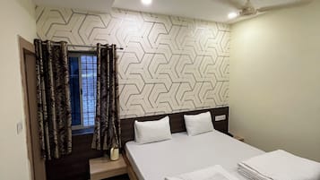 Ein Schlafzimmer mit Bett, einem fenster mit Vorhängen, einem Deckenventilator und einer Wand mit Muster.
