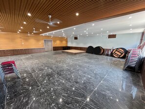 A spacious room with a polished marble floor, wooden panel ceiling, and ceiling lights.