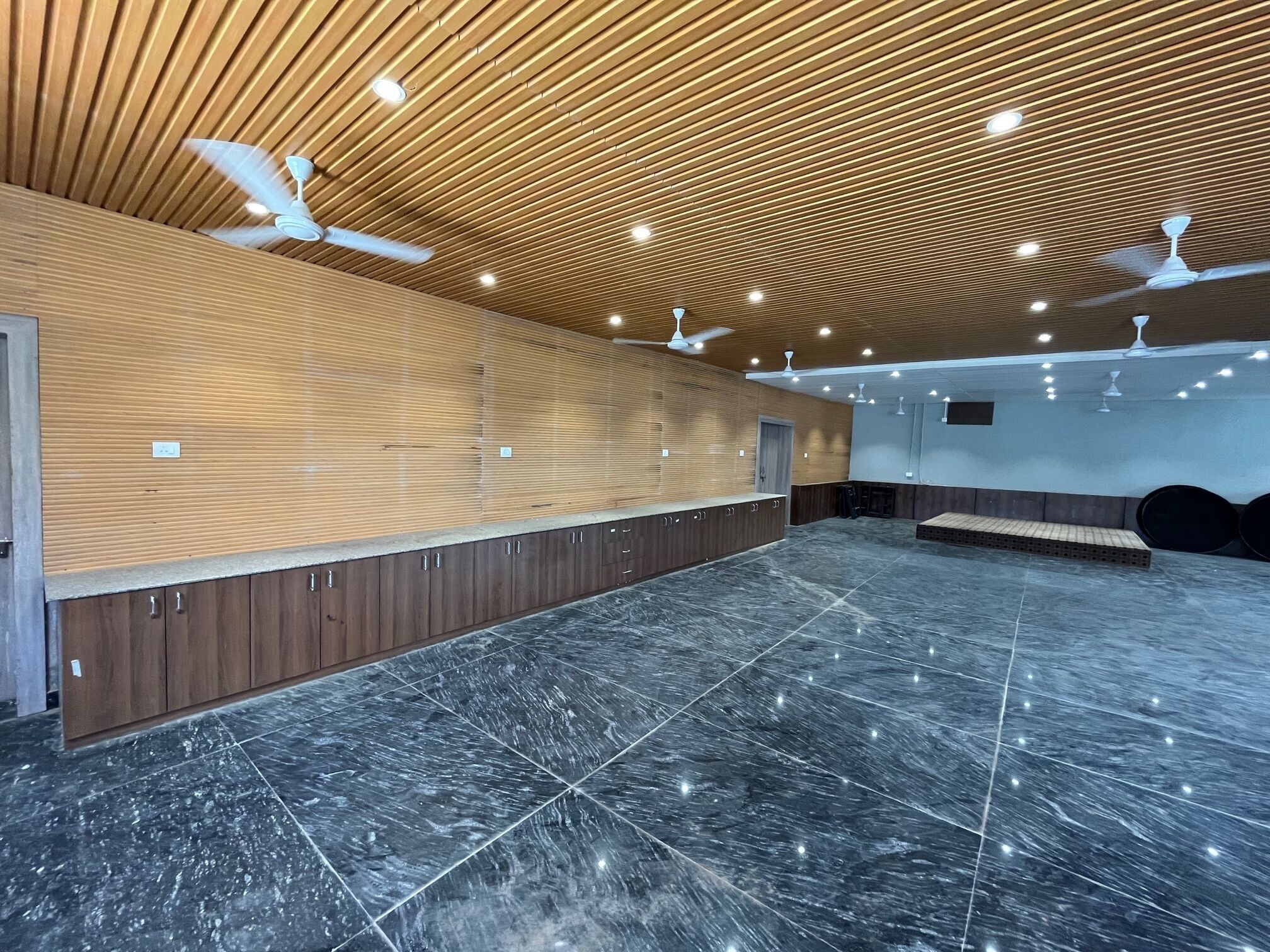 Eine geräumige Lobby mit schrägverlegt Deckenbalken aus Holz, Marmorböden und Deckenventilatoren.