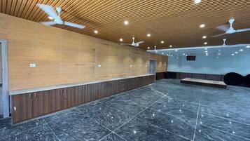 Eine geräumige Lobby mit schrägverlegt Deckenbalken aus Holz, Marmorböden und Deckenventilatoren.