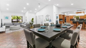 Un'ampia zona giorno e pranzo open space, con un tavolo da pranzo grande apparecchiato per sei persone, circondato da sedie grigie rivestite in tessuto.
