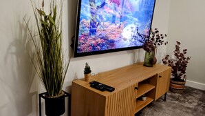 Una TV a schermo piatto montata a parete sopra un mobile in legno con un telecomando sopra.