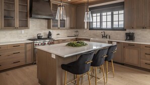 A modern kitchen with a central island, bar stools, and a large window providing natural light. - Modern Mountain House w/ Private Hot Tub (Big Sky)