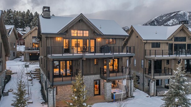 A large, multi-story wooden house with a stone foundation, multiple balconies, and large windows. - Modern Mountain House w/ Private Hot Tub (Big Sky)