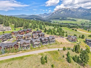 A residential area with multiple two-story houses featuring balconies and a mountainous backdrop. - Modern Mountain House w/ Private Hot Tub (Big Sky)
