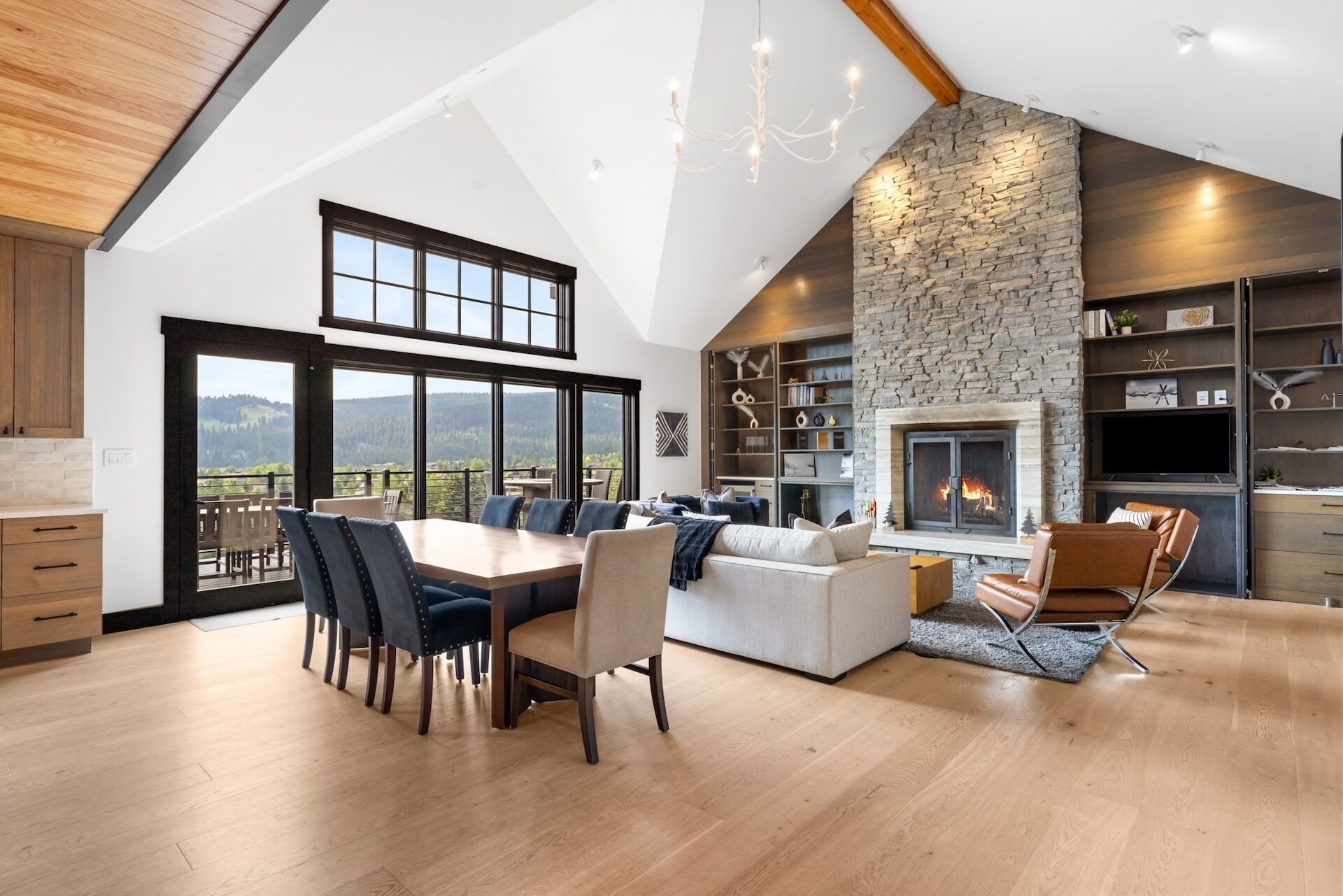 A spacious living area with a fireplace, a dining table with chairs, and a view of the outdoors.