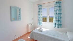 Une chambre avec deux lits, une fenêtre avec des rideaux, un miroir et un radiateur.