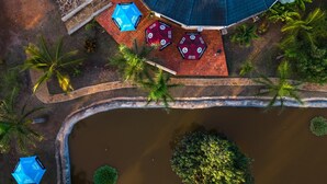 Vista aérea de un resort con piscina, palmeras y zonas de estar al aire libre.