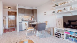 Un soggiorno moderno con zona pranzo, cucina e un mobile TV con libri e giochi.