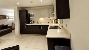 Une cuisine moderne avec des meubles de couleur sombre, un four à micro-ondes et un évier.