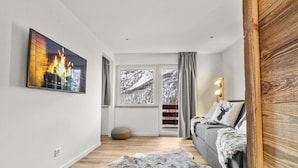 Een moderne woonkamer met een open haard, een groot raam met sneeuwlandschap, een gezellige bank en een houten accentmuur.