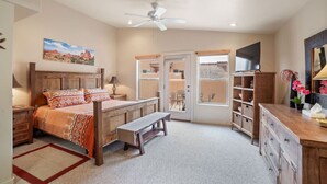 A bedroom with a bed, a bench, a desk, and a wardrobe. - Rim Village X3 - Large Patio & Private Hot Tub (Moab)