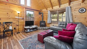Ein gemütliches Blockhausschlafzimmer mit Kamin, Ledersofa und Fernseher.
