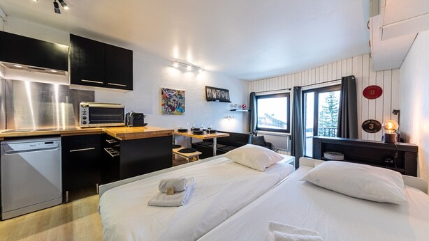 A modern hotel room with a kitchenette, a bed with white linens, a dining area, and a large window with a view. - Immodreams - L'Ardoisière - Avoriaz (Avoriaz)