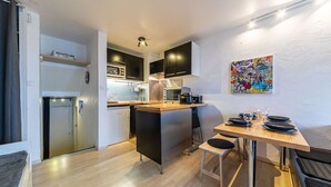 A compact kitchen with modern appliances, a dining area with a wooden table and chairs, and a colorful abstract painting on the wall. - Immodreams - L'Ardoisière - Avoriaz (Avoriaz)
