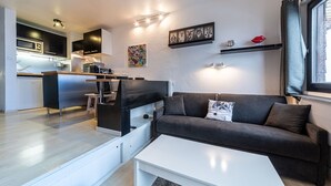 A modern living space with a sofa, coffee table, kitchen area, and artwork on the walls. - Immodreams - L'Ardoisière - Avoriaz (Avoriaz)